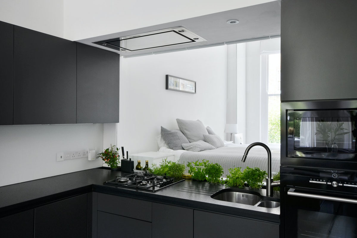 A Glass Window Separates the Kitchen and Bedroom of this Small London Flat